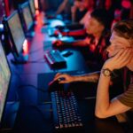 a man sitting in a gaming cafe playing Rogue Conflict on a PC