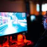 a man playing Splitgate 2 on his PC in a dark room with RGB lights