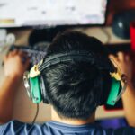 a man wearing headphones while playing Civ VII on his home PC