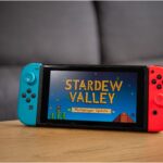 a Nintendo Switch with Stardew Valley on in standing on a wooden table in the living room