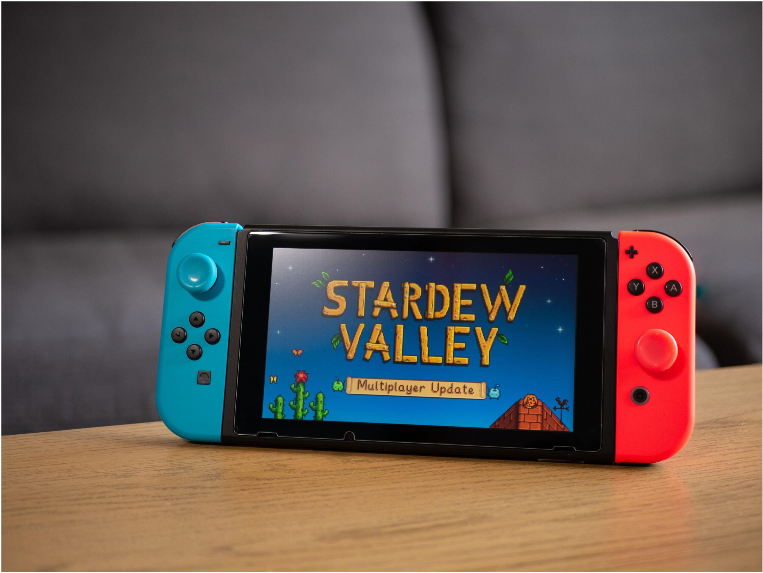 a Nintendo Switch with Stardew Valley on in standing on a wooden table in the living room