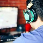 a man playing Crusader Kings III on his PC while wearing headphones