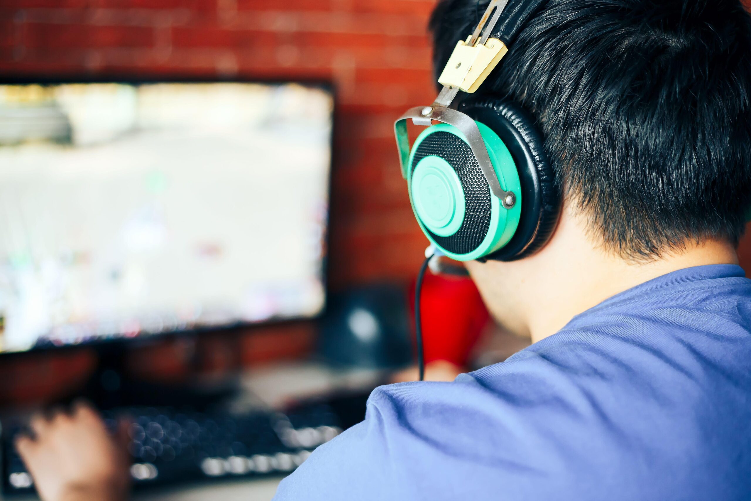 a man playing Crusader Kings III on his PC while wearing headphones