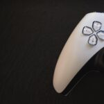a black and white PS5 controller on a black table to represent the console Wildgate will be released on