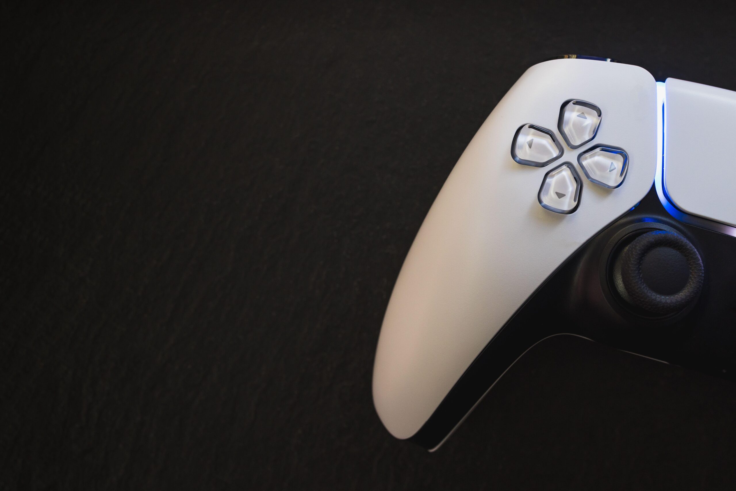 a black and white PS5 controller on a black table to represent the console Wildgate will be released on