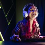 a woman laughing while playing Cairn on her PC in an RGB lit room